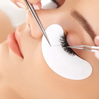 A woman having her eyelashes trimmed with scissors during a beauty treatment.