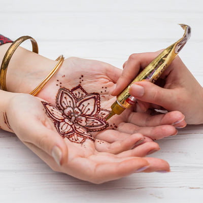 A woman holding a pen and henna in her hands, showcasing her artistic skills and cultural appreciation.